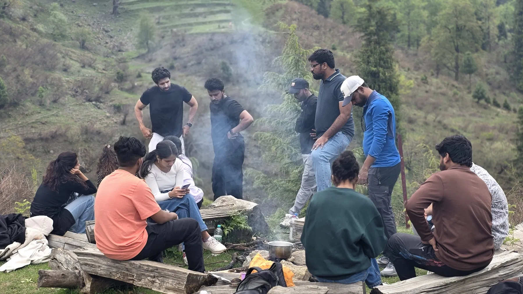 A larger Safar group waiting around a smoky outdoor cooking area