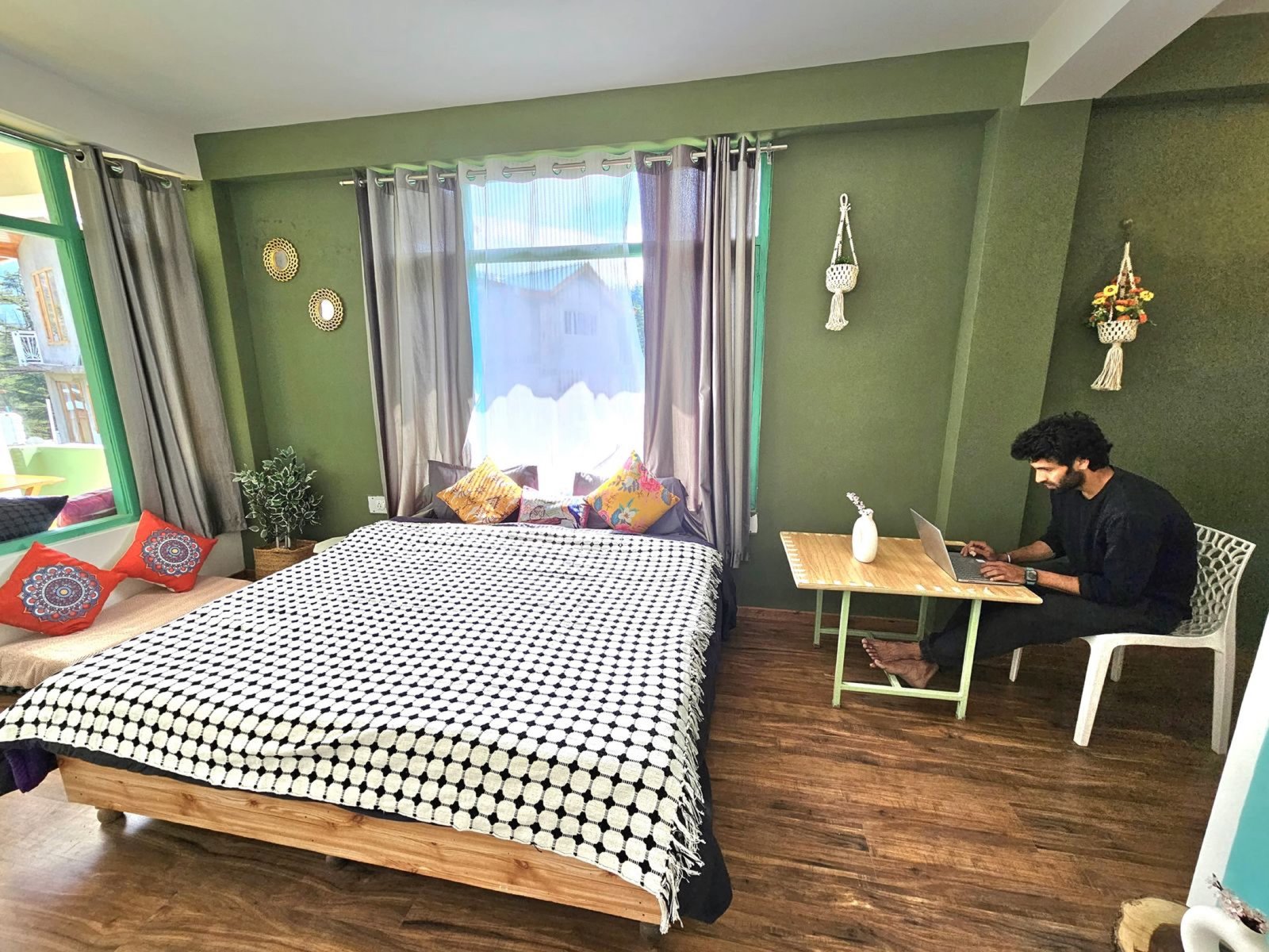 Guest working at the desk inside Safar Hostel's spacious Corner Room